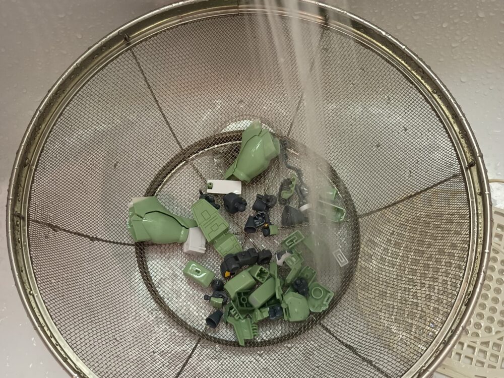 ざるに入れたパーツを流水で濯ぐ